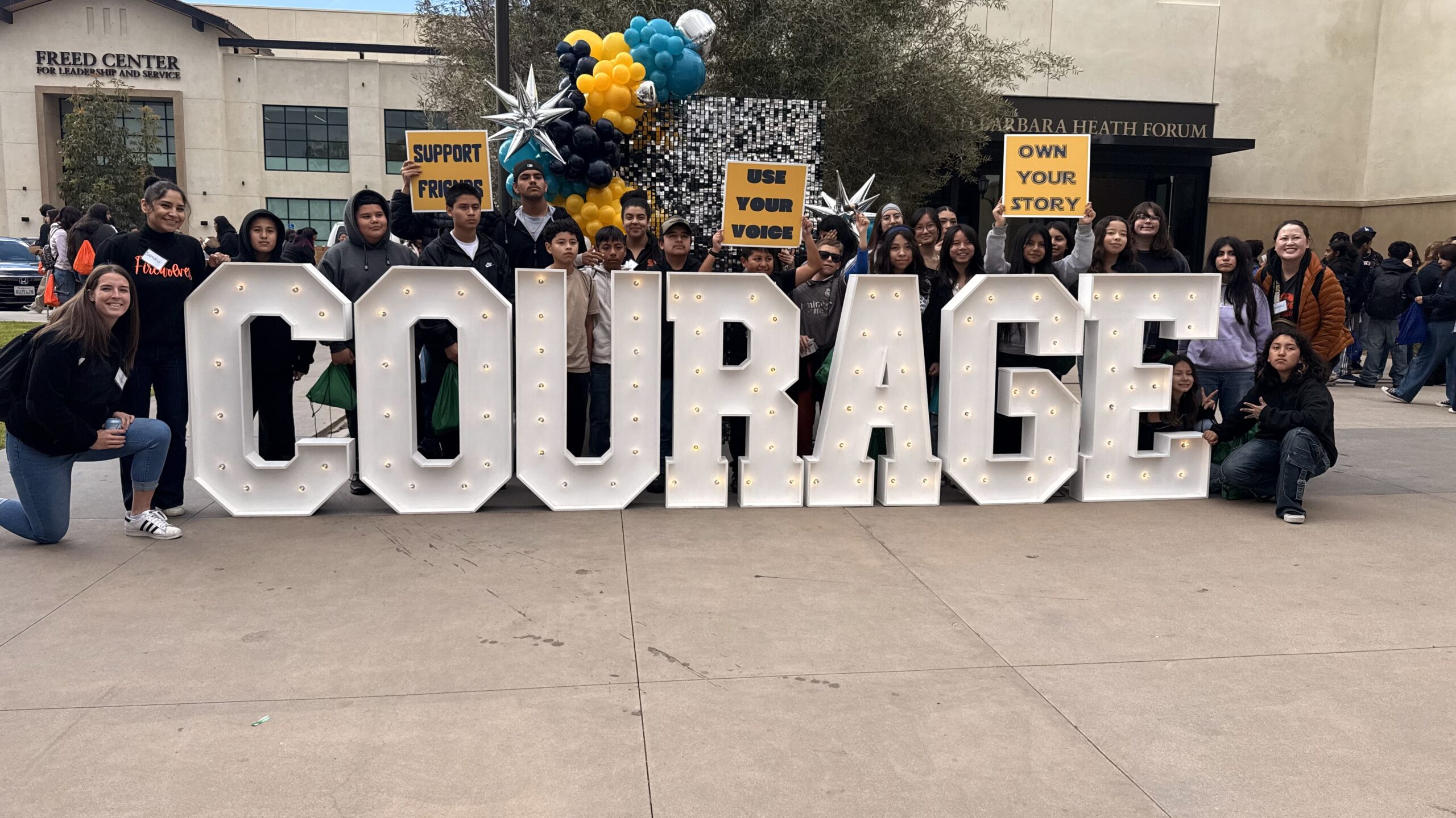 Samueli Academy Students next to a sign that says "Courage"