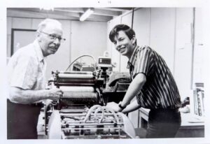 Young Ken Kafton operating a printing press alongside Lin Trestrail in the San Joaquin School District print shop, early 1970s