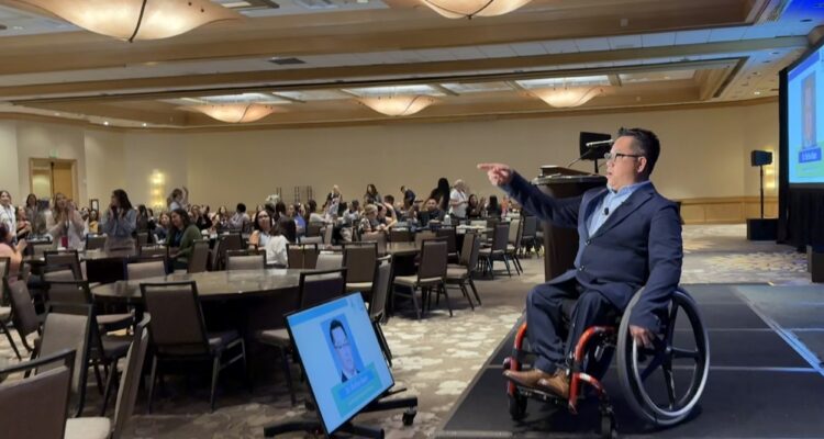 Dr. Stefan Bean speaks from the stage to an audience of mental health professionals at the School-Based Mental Health Summit in Costa Mesa.