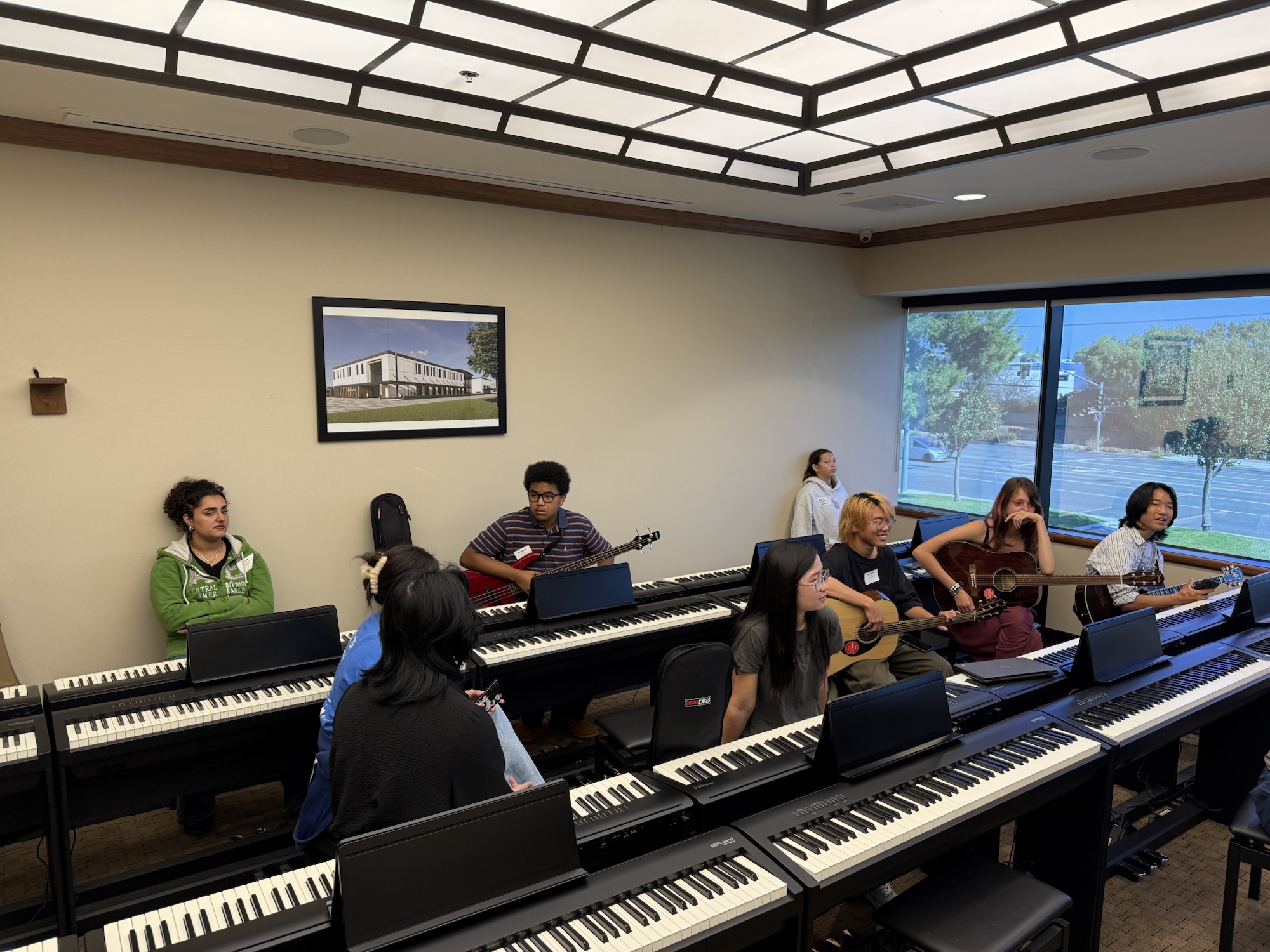 High school students sit at keyboards and hold guitars during a songwriting session in a classroom at OC Music & Dance.