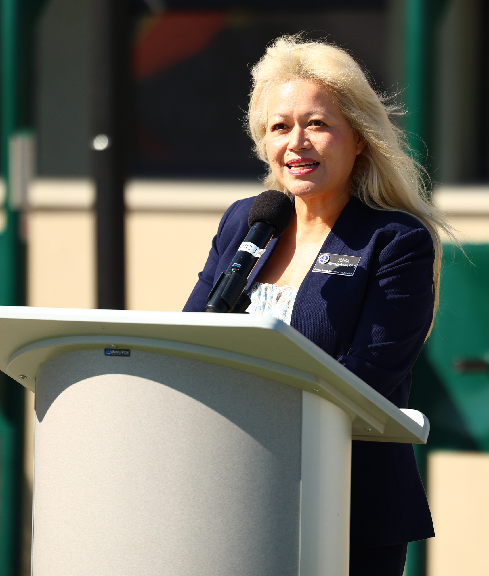 Dr. Maria Martinez-Poulin speaks at a podium during a ceremony at Joint Forces Training Base in Los Alamitos, where Sunburst Youth Academy received OCDE’s inaugural School Impact Award.