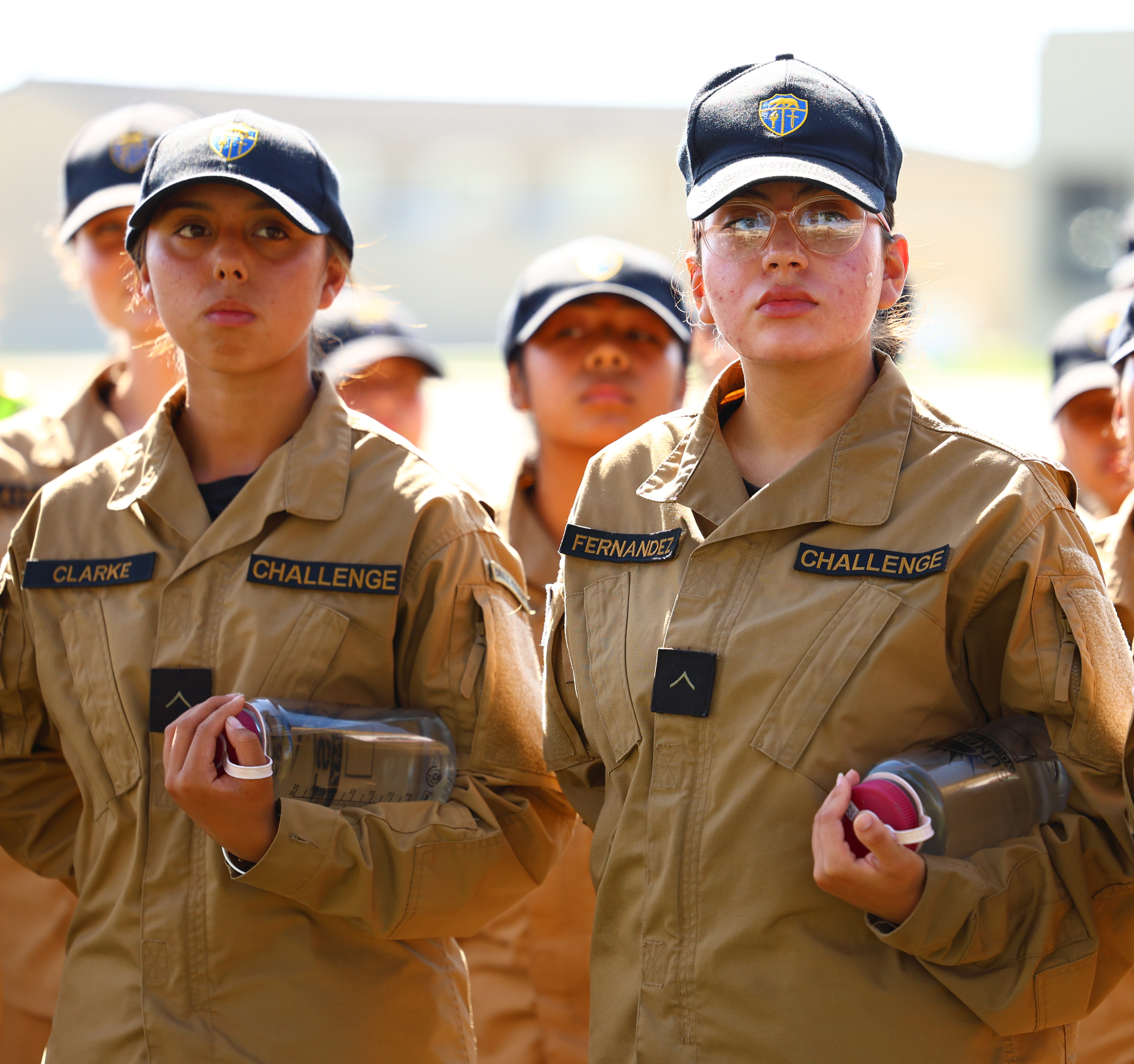 Two Sunburst Youth Academy cadets in tan uniforms and navy caps stand at attention during a ceremony at Joint Forces Training Base in Los Alamitos, where the academy was recognized as one of 12 campuses to receive OCDE’s inaugural School Impact Award.