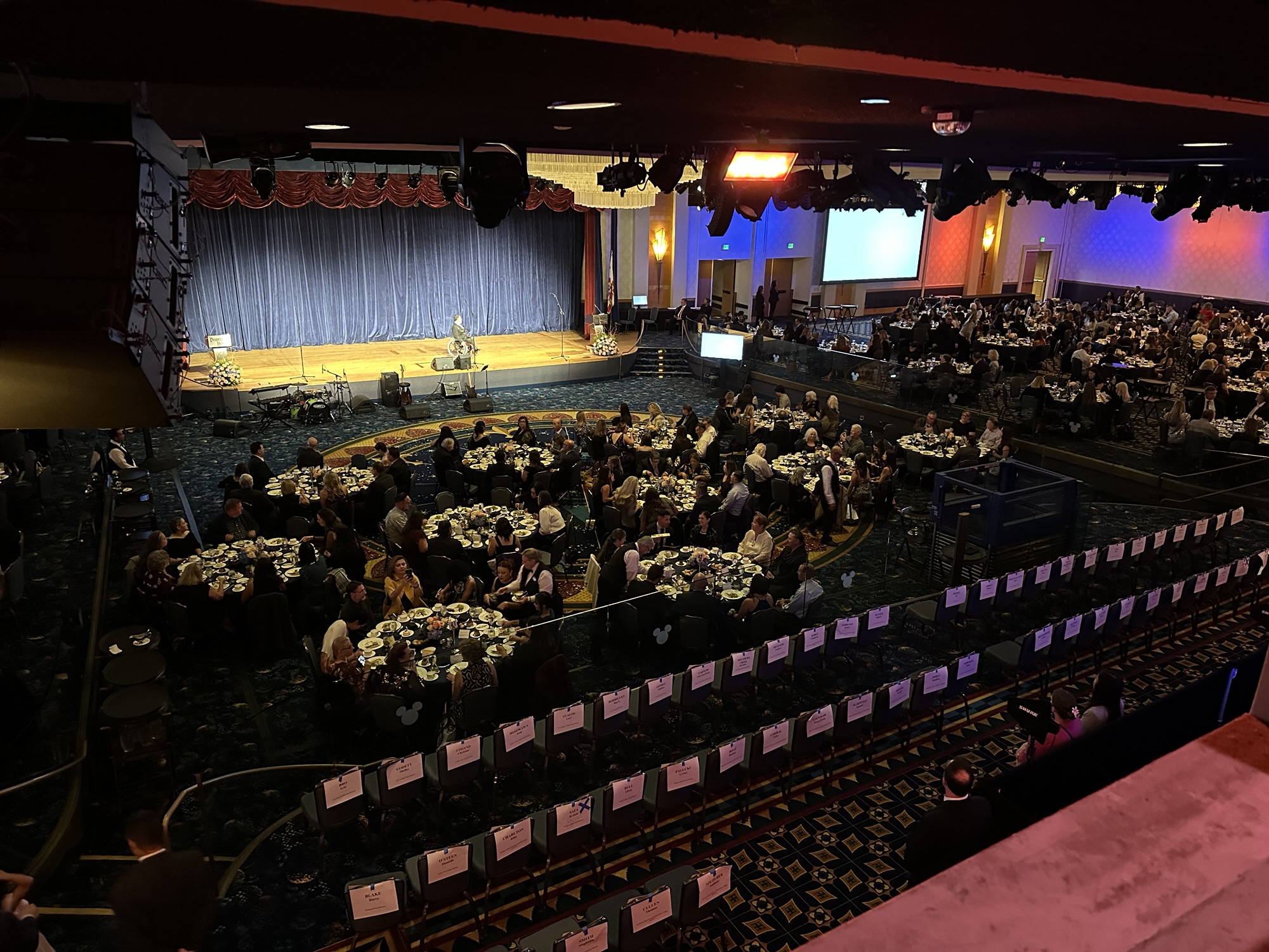 Wide view of the Disneyland Hotel ballroom showing dozens of round tables filled with guests attending the 2026 Orange County Teachers of the Year gala, with a stage set for presentations and performances.