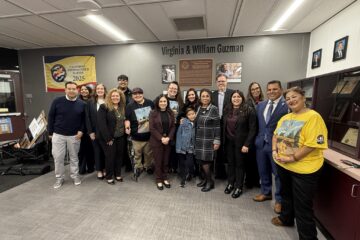 Santa Ana Unified School District Board of Education members, district leaders and staff stand with Guzman family members inside the school office during the dedication ceremony.