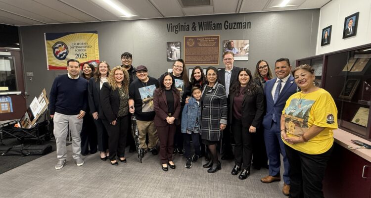 Santa Ana Unified School District Board of Education members, district leaders and staff stand with Guzman family members inside the school office during the dedication ceremony.