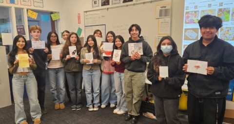 Students from Samueli Academy’s Helping Hands Club hold handmade cards created for patients at a local children’s hospital.