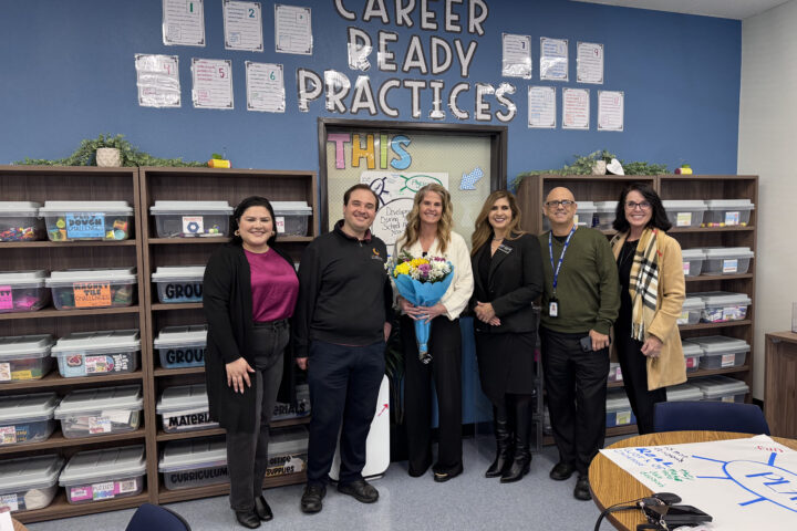 Casie Hollenbeck (center) stands with a bouquet during a CTE Month recognition visit alongside Jacquelyn Leyva, Steven Kahn, Dr. Jacqueline Cardenas, Chris Alfieri and Machele Kilgore.