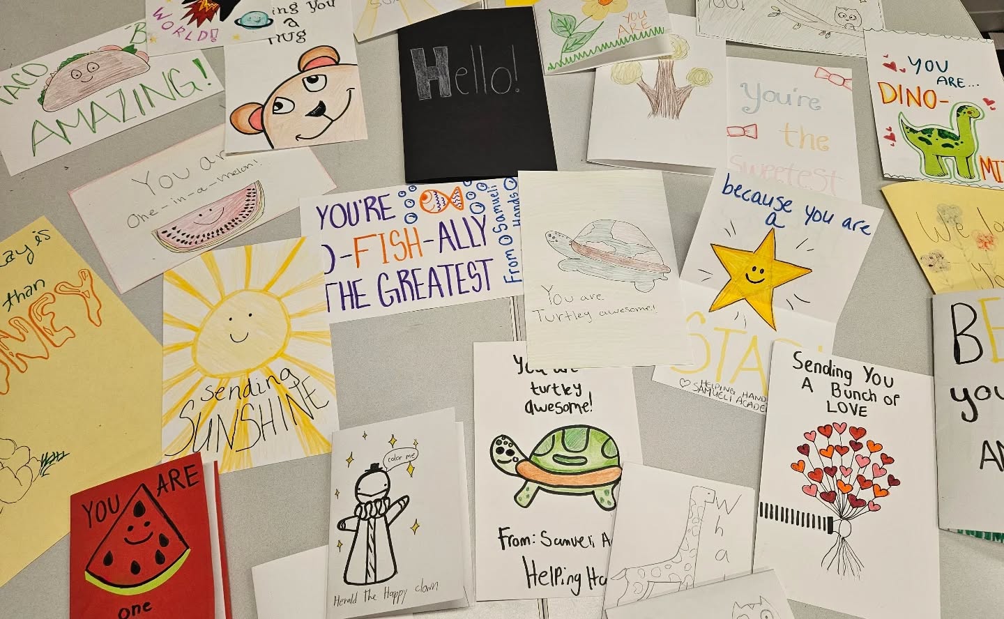 Handwritten and illustrated cards created by Samueli Academy students are displayed on a table during the Great Kindness Challenge.
