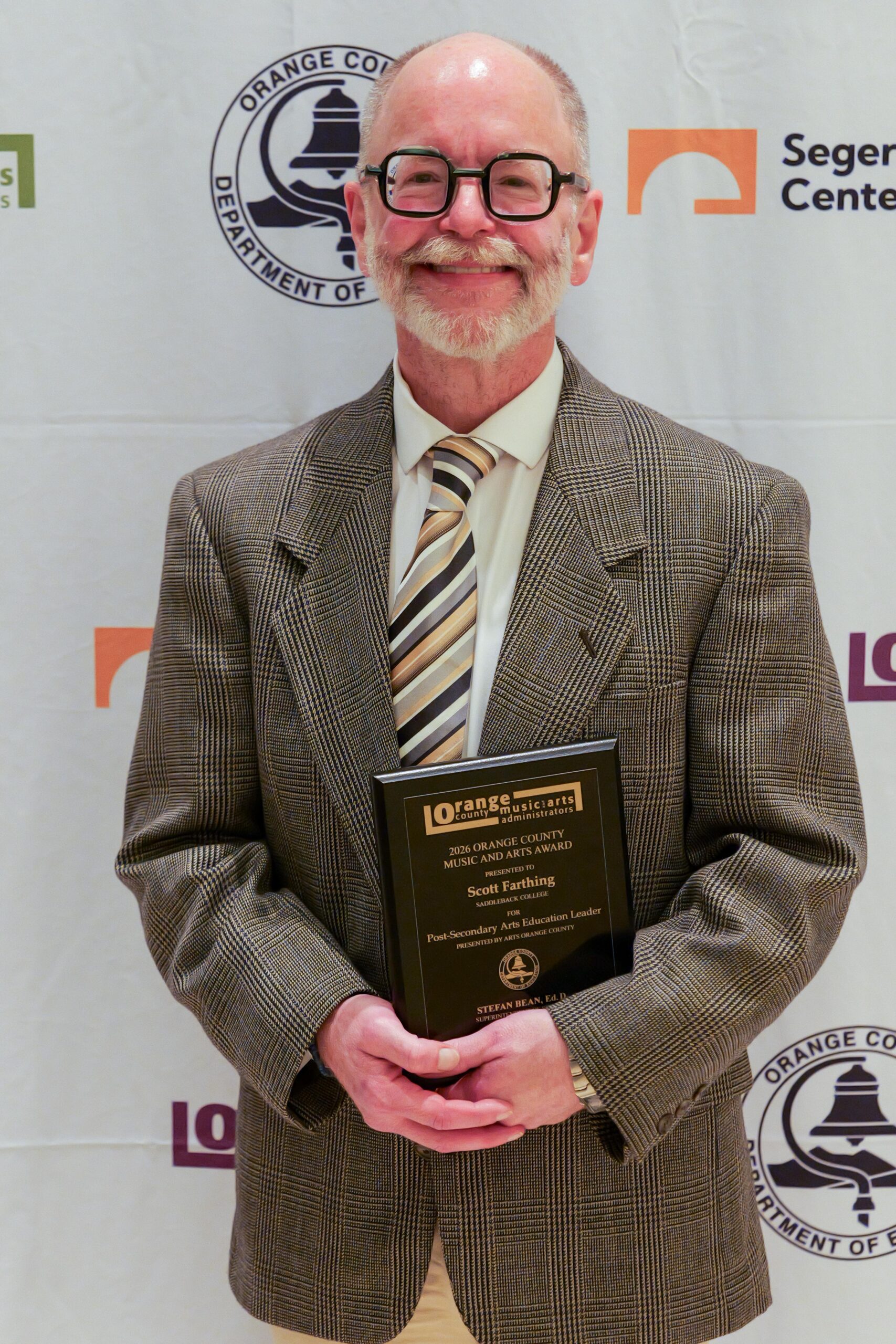Scott Farthing of Saddleback College holds his award after being recognized as the OCMAA Award recipient for Post-Secondary Arts Education Leader at the 2026 ceremony.