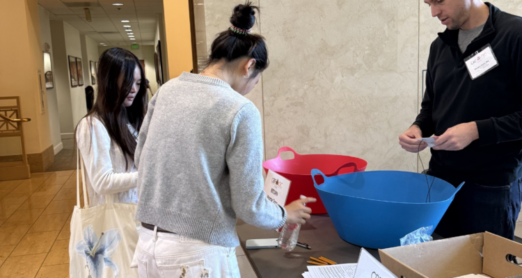 High school students return surveys at a registration table during the Law Day Conference at Chapman University while a volunteer assists them.