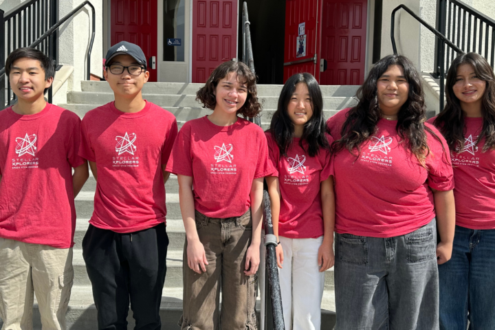 Six students wearing red StellarXplorers shirts stand together for a team photo.