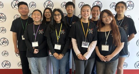 University High School students wearing medals in front of a California Academic Decathlon backdrop.
