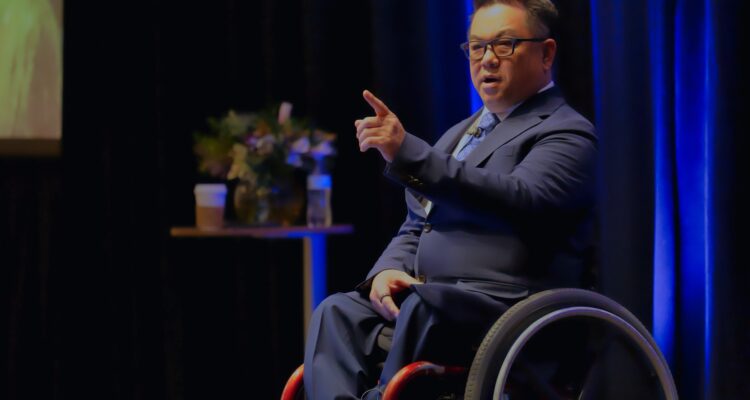 County Superintendent Dr. Stefan Bean speaks from the stage to a seated audience during the Orange County State of Education event