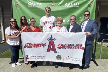 Trustee Alva Alvarez, Assistant Superintendent Dena Melland, Assistant Superintendent Dr. Yadira Moreno, Los Angeles Angels pitcher Jack Kochanowicz, Board President Jackie Filbeck, Superintendent Jesús Chavarria and Assistant Superintendent Matthew Slusser pose with an Angels Adopt-A-School banner at Gauer Elementary School in Anaheim.