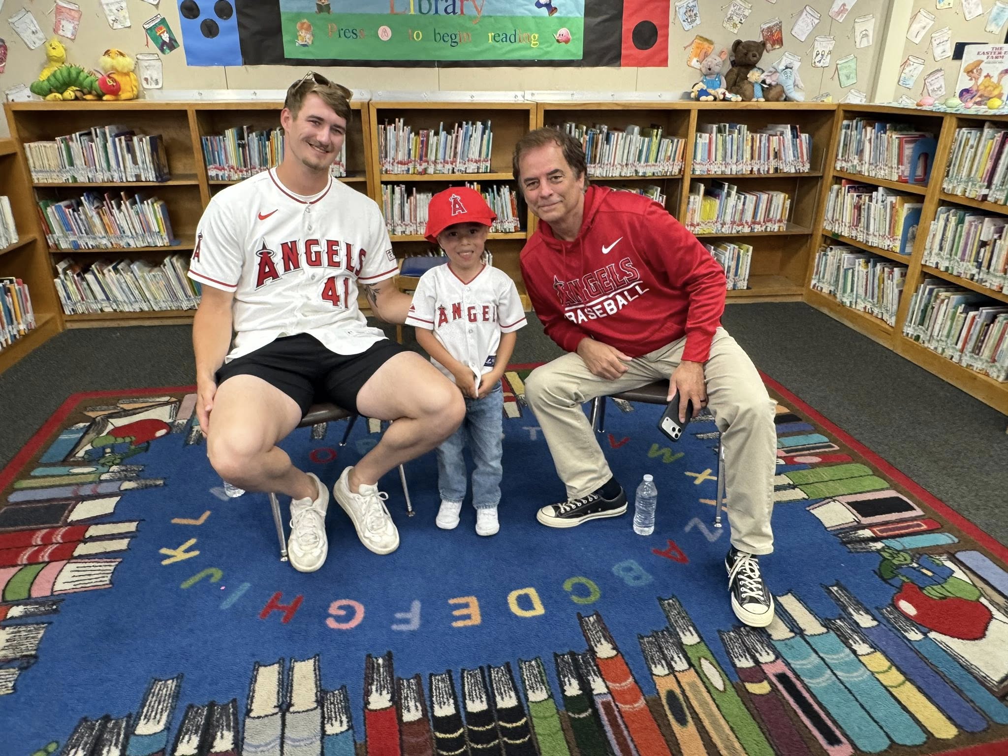 Los Angeles Angels pitcher Jack Kochanowicz, left, poses with a student and sports radio host Roger Lodge during a visit to Gauer Elementary School in Anaheim as part of the Angels Adopt-A-School program.