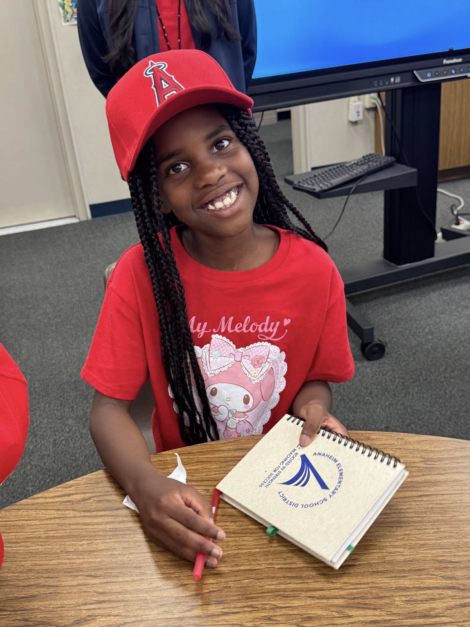 A student smiles while holding a notebook during an Angels Adopt-A-School visit at Gauer Elementary School in Anaheim.