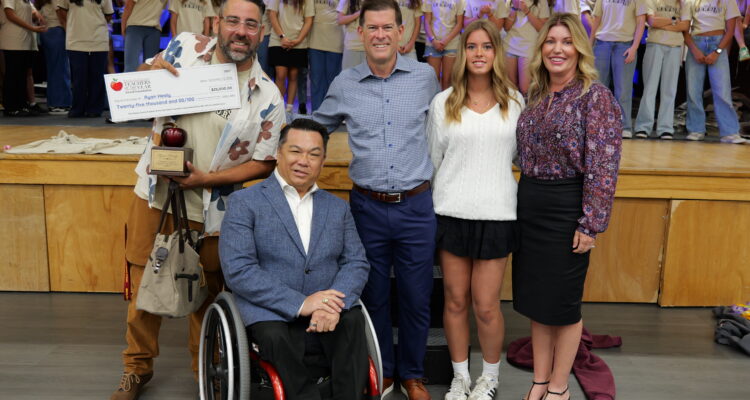 2027 Orange County Teacher of the Year Ryan Healy receives a $25,000 check from the William, Jeff and Jennifer Gross Family Foundation while receiving congratulations from Superintendent Dr. Bean and his Marco Forster Middle School musical theater students.