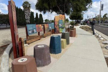 Interpretive panels and seating along the Mendez Freedom Trail in Westminster, as a man takes a photo and attendees gather in the background during the dedication ceremony.