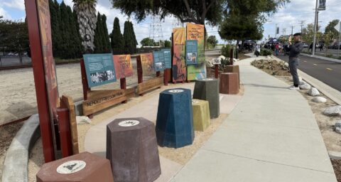 Interpretive panels and seating along the Mendez Freedom Trail in Westminster, as a man takes a photo and attendees gather in the background during the dedication ceremony.