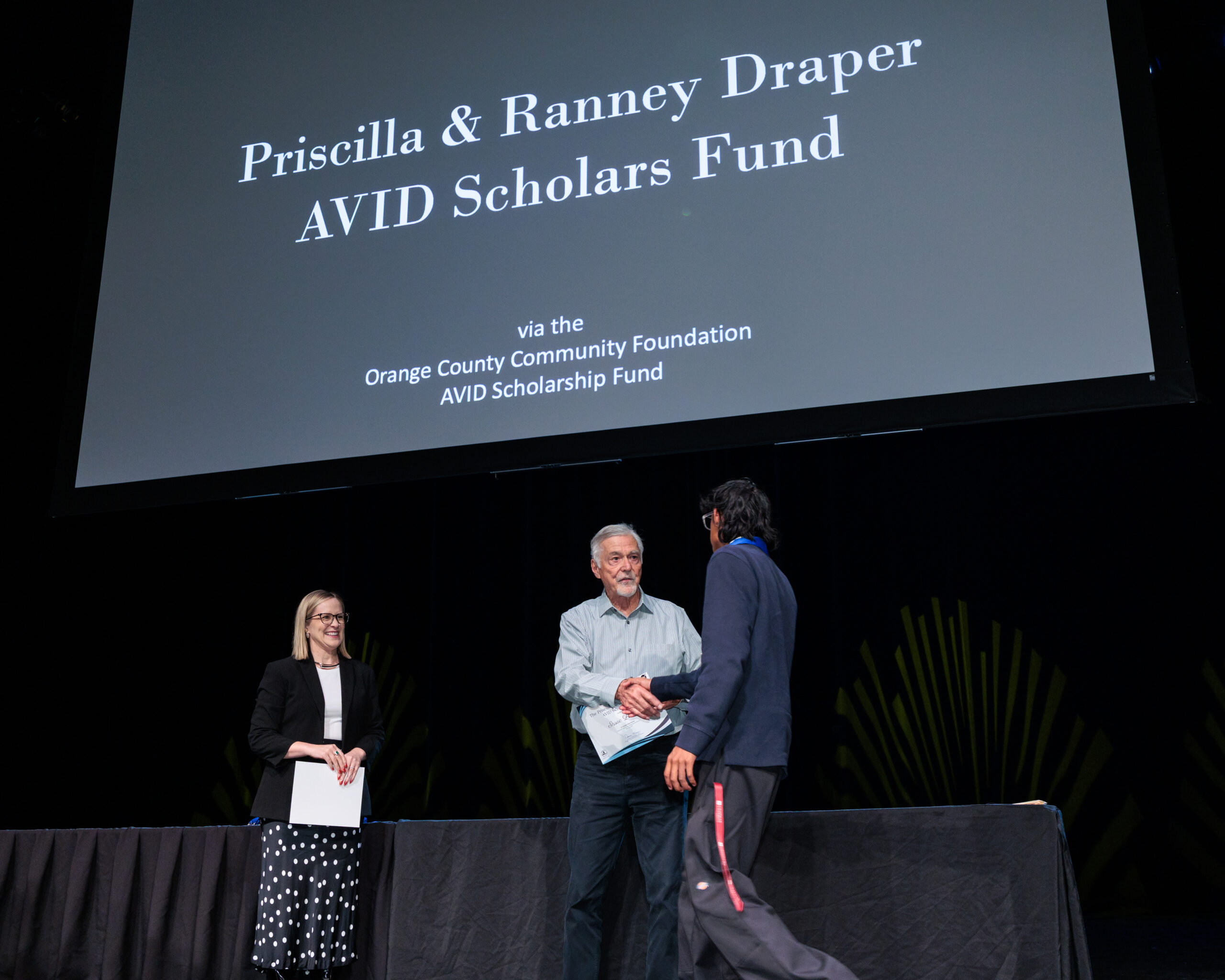 An AVID senior receives a Priscilla and Ranney Draper AVID Scholars Fund scholarship during the 2026 OC AVID Senior Standout Recognition and Scholarship Presentation at the Irvine Barclay Theatre.
