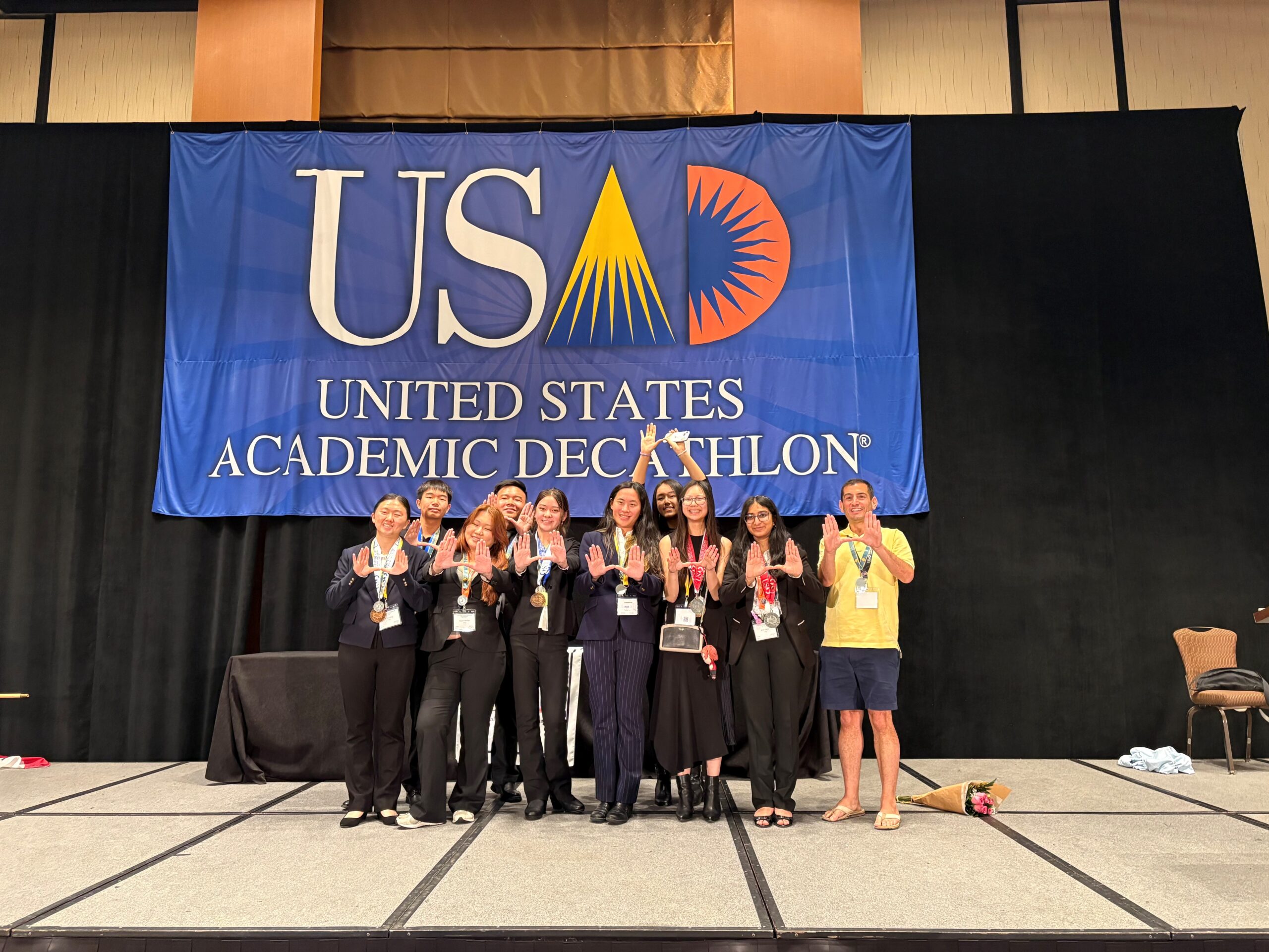 University High School’s Academic Decathlon team and coach Christopher Esposito pose on stage during the awards ceremony at the 2026 United States Academic Decathlon National Competition in Garden Grove. 