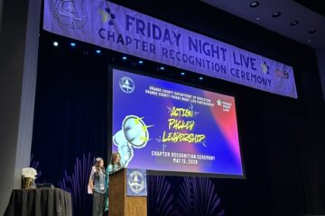 Two students speak at a podium onstage during the Friday Night Live Chapter Recognition Ceremony at the Barclay Theatre.