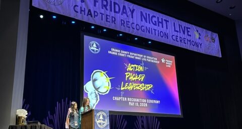 Two students speak at a podium onstage during the Friday Night Live Chapter Recognition Ceremony at the Barclay Theatre.