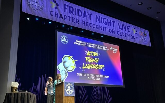 Two students speak at a podium onstage during the Friday Night Live Chapter Recognition Ceremony at the Barclay Theatre.