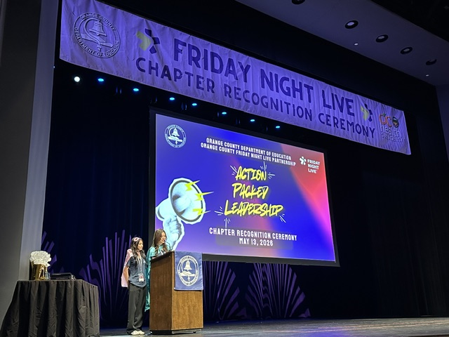 Two students speak at a podium onstage during the Friday Night Live Chapter Recognition Ceremony at the Barclay Theatre.