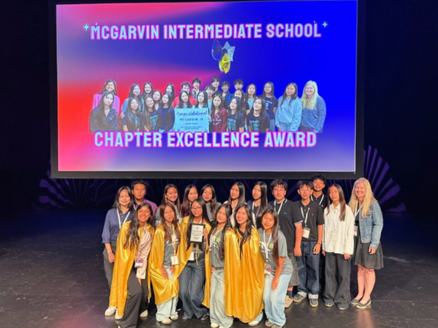 Students and advisors from McGarvin Intermediate School pose onstage with a Chapter Excellence Award during the Friday Night Live recognition ceremony.