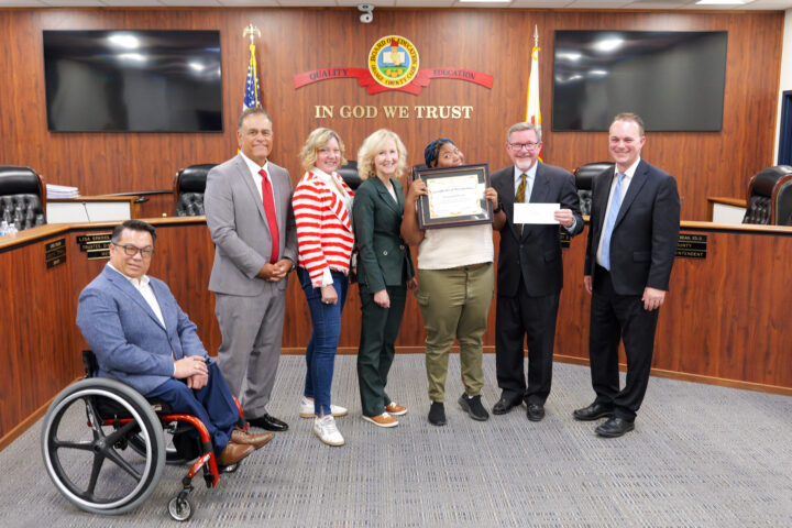 Connections student Savannah accepts her award alongside members of the Orange County Board of Education and Superintendent Dr. Stefan Bean.