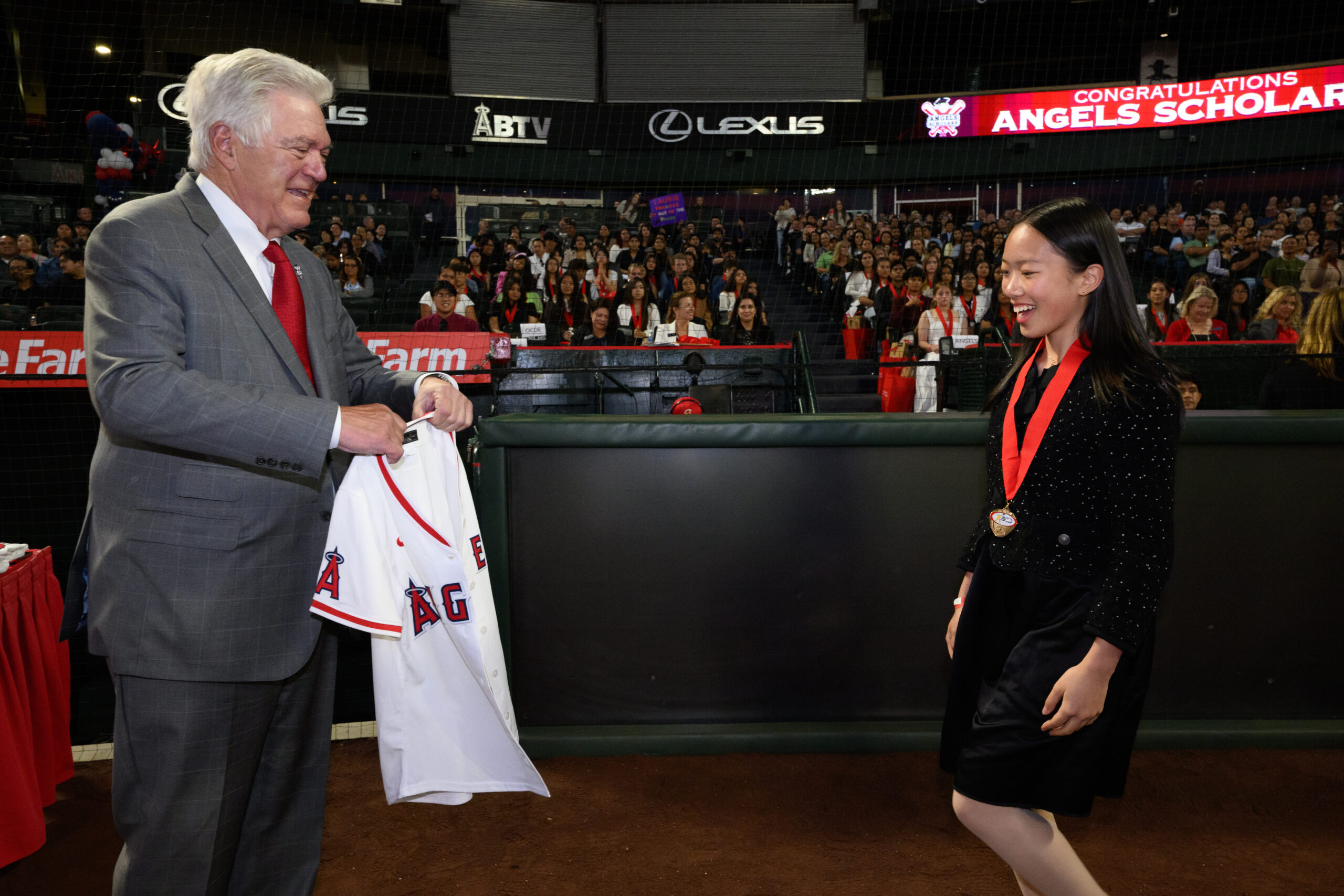 Dennis Kuhl, chairman of Angels Baseball, presents an Angels jersey to a student during the 2026 AVID 8th Grade Standout Recognition ceremony at Angel Stadium.