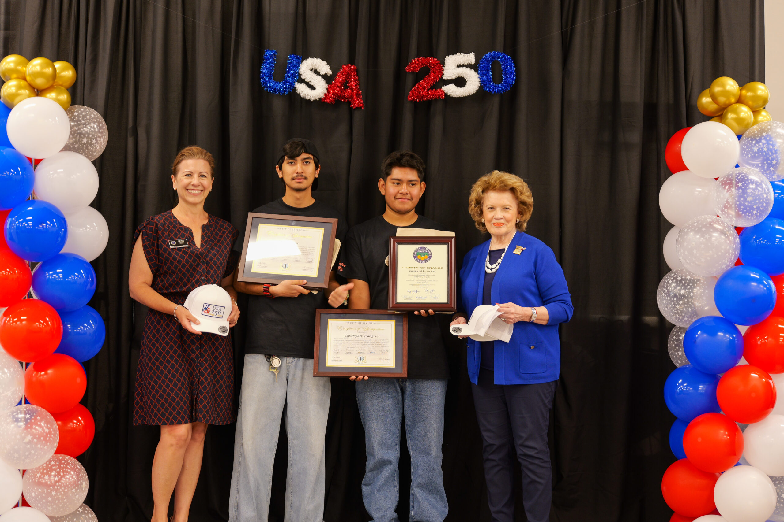 Students from Gilbert High School hold awards recognizing their winning rock song, "The Moment," during the USA 250-OC Theme Song Competition awards ceremony.