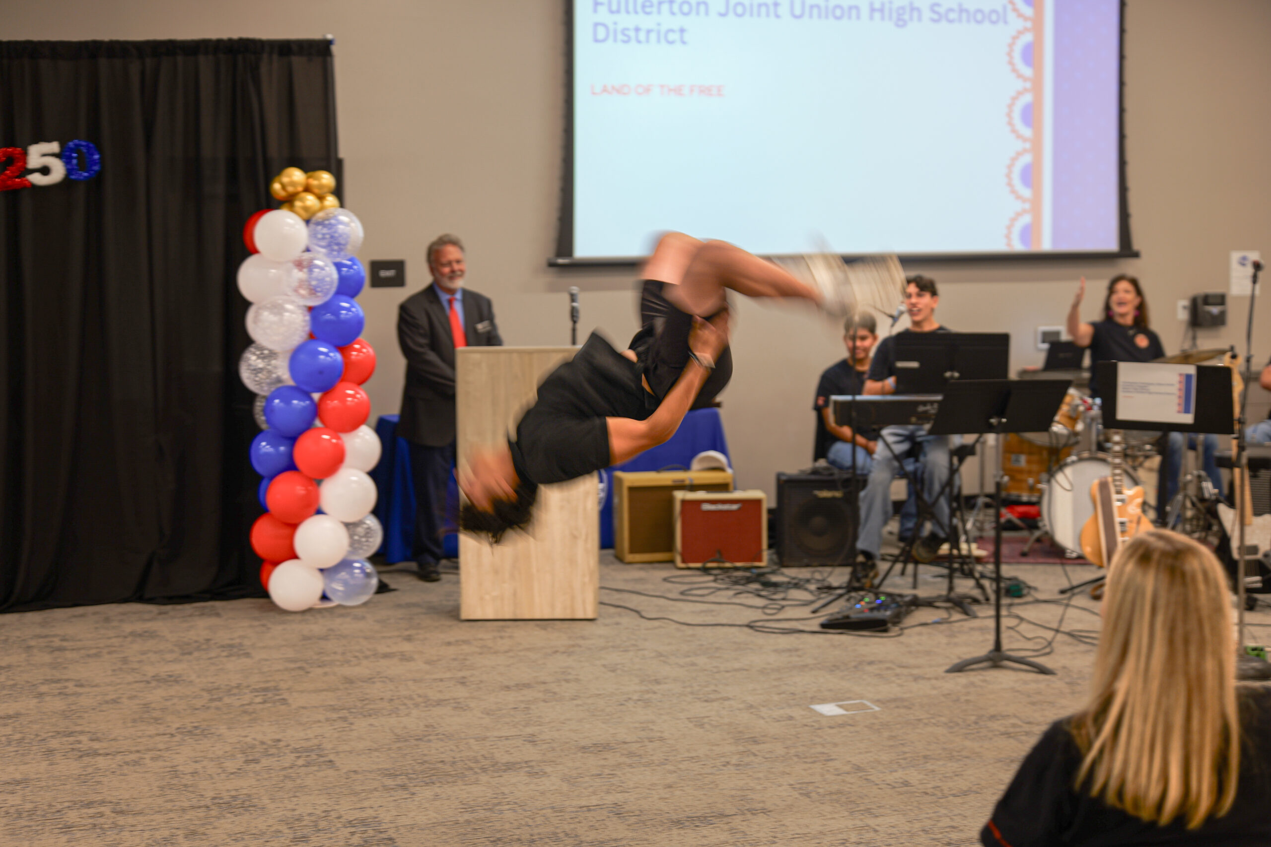A student performs a backflip during a hip-hop performance at the USA 250-OC Theme Song Competition showcase.
