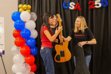 Ella Wu accepts a guitar prize from Fender Education representatives during the USA 250-OC Theme Song Competition awards ceremony.