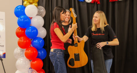 Ella Wu accepts a guitar prize from Fender Education representatives during the USA 250-OC Theme Song Competition awards ceremony.