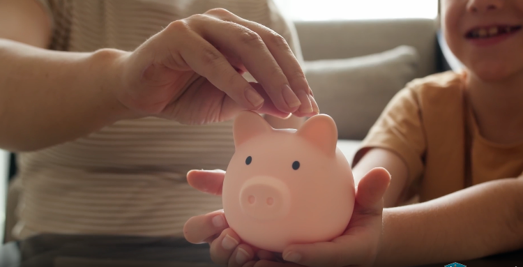 An adult and child place coins into a pink piggy bank, representing college and career savings opportunities available through the CalKIDS program.
