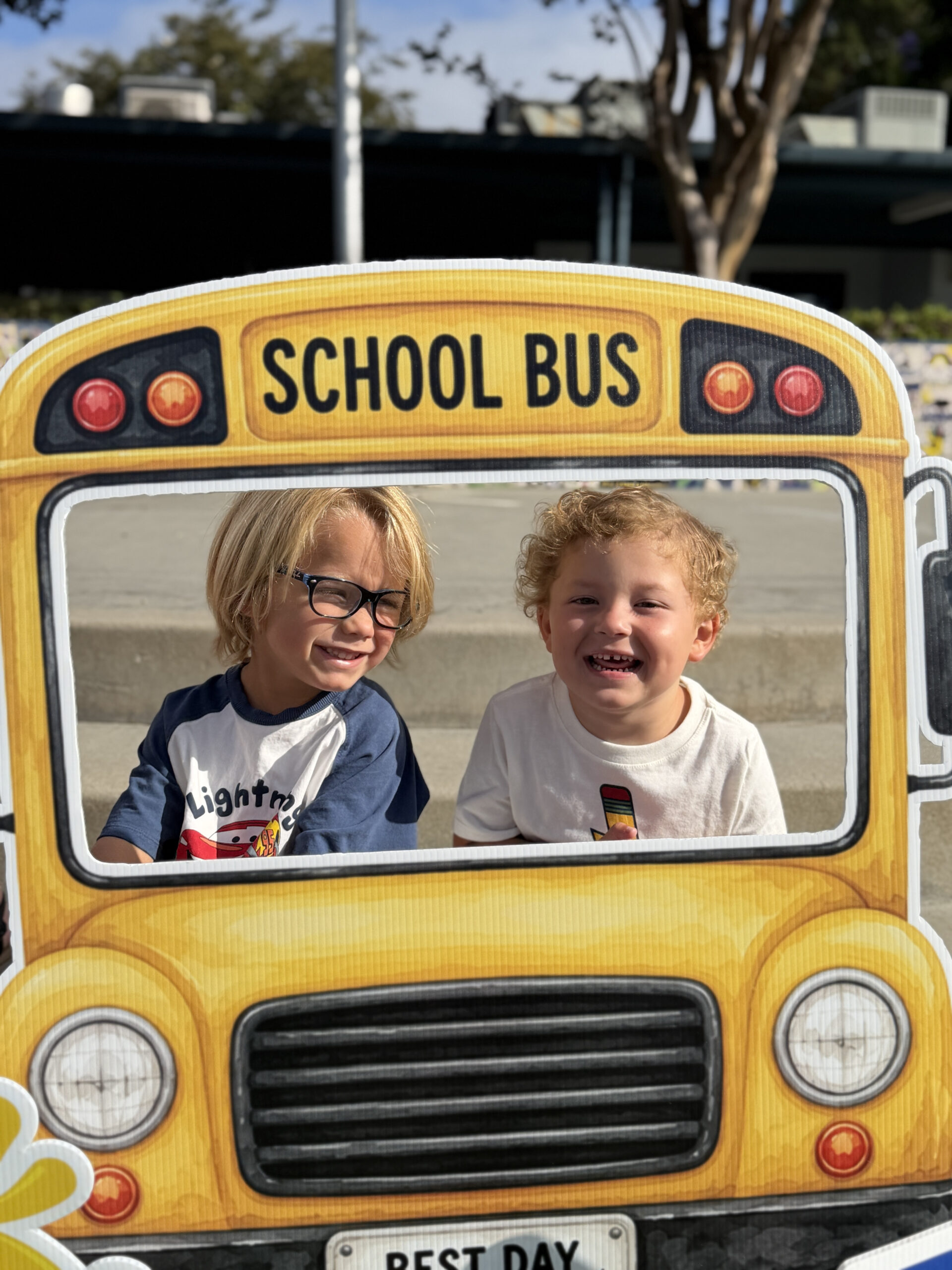 Two young students smile while posing behind a school bus photo prop during the first day of school at Weaver Elementary School in Los Alamitos on July 29.
