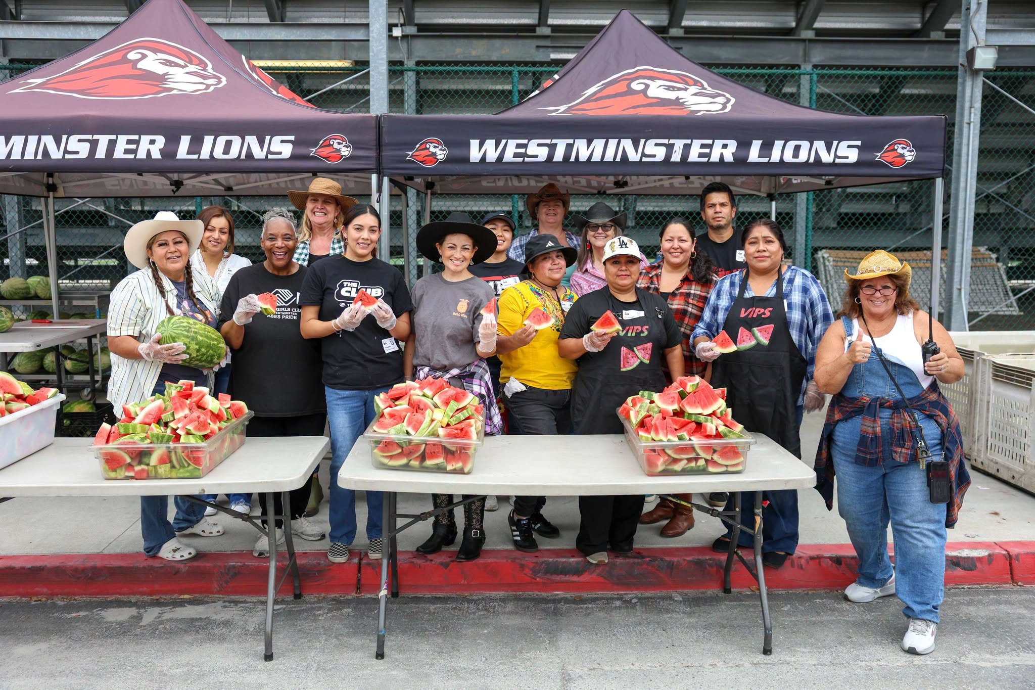 Westminster High School staff and volunteers gather with freshly sliced watermelon during the ninth annual harvest at the Giving Farm.