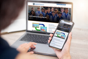 Person viewing OCDE’s redesigned website on a laptop and smartphone, showing the site’s responsive layout across desktop and mobile devices.