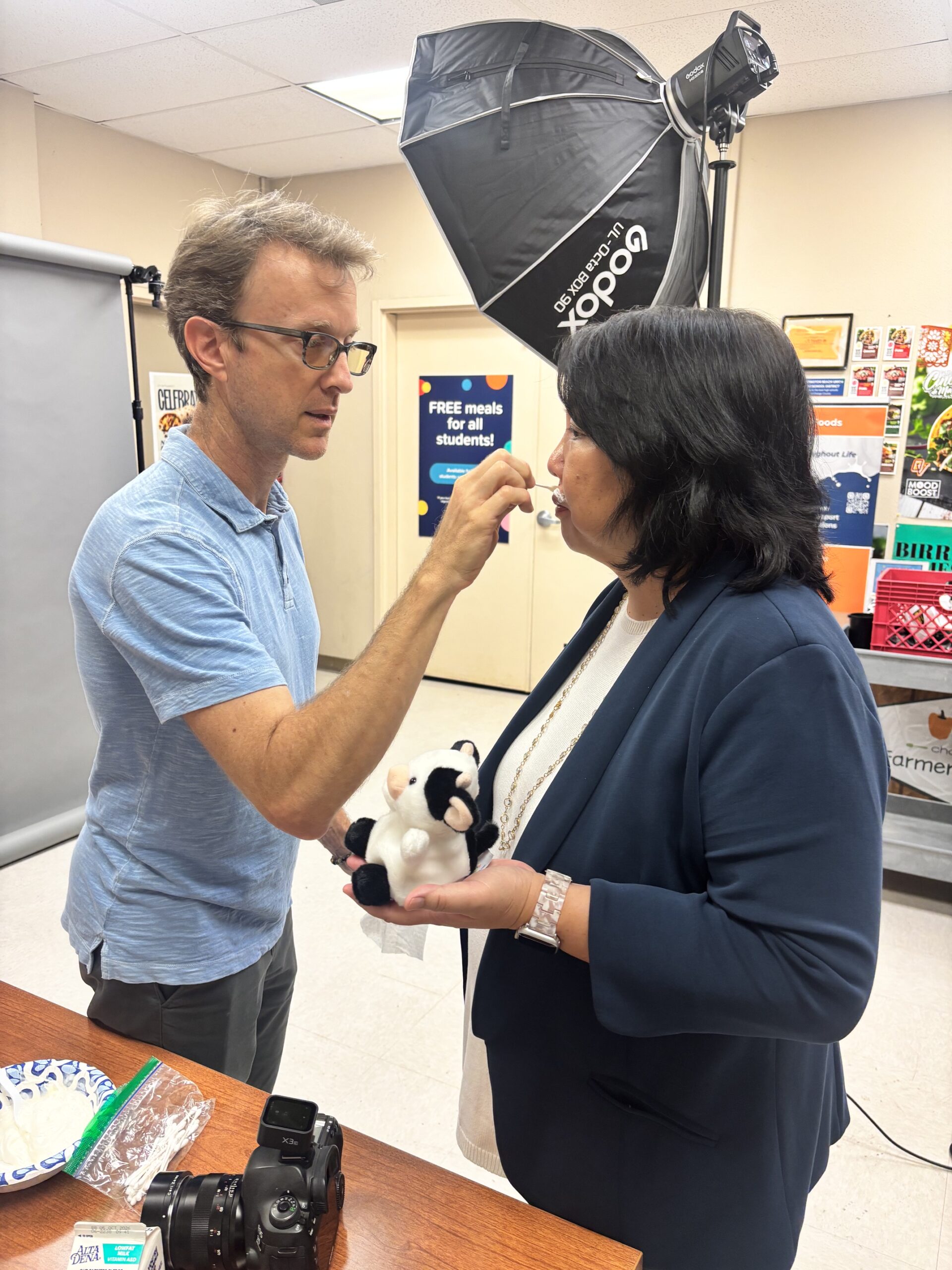 A member of the Got Milk? production team applies the campaign's signature milk mustache to Huntington Beach Union High School District Superintendent Dr. Carolee Ogata during a photo shoot at the district's Nutrition Services office.