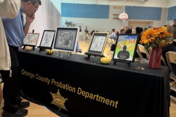Onlookers examine the five winning drawings at the Ninth Annual Essay and Visual Arts Contest for incarcerated youth at Otto A. Fischer School within Orange County Juvenile Hall.