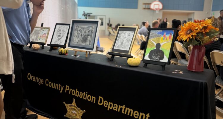 Onlookers examine the five winning drawings at the Ninth Annual Essay and Visual Arts Contest for incarcerated youth at Otto A. Fischer School within Orange County Juvenile Hall.