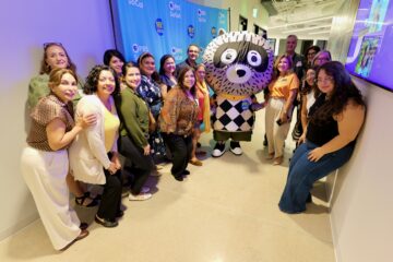 Attendees pose with Carl the Collector and OCDE Language Services Coordinator Natalia Abarca, in orange, during the department’s International Translation Day celebration at PBS SoCal studios in Costa Mesa.
