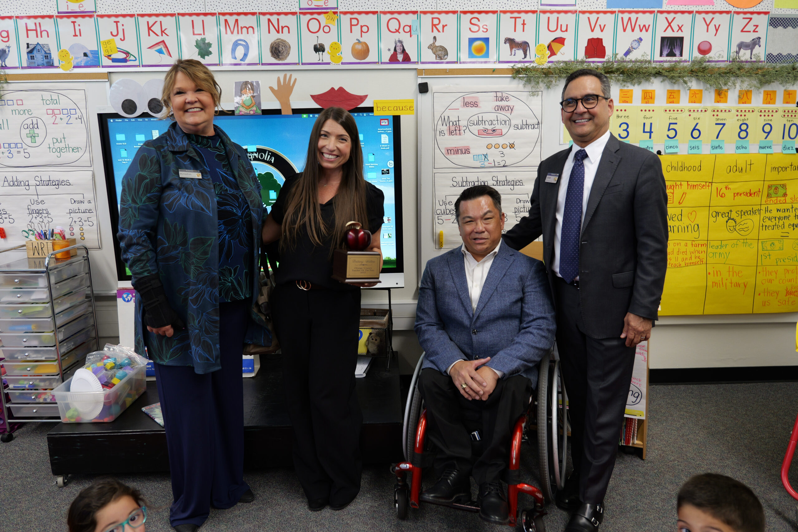 Brittany Walters, second from left, poses with Orange County Superintendent of Schools Dr. Stefan Bean, seated, and representatives from premier sponsor SchoolsFirst Federal Credit Union after receiving her 2027 Orange County Teacher of the Year award.