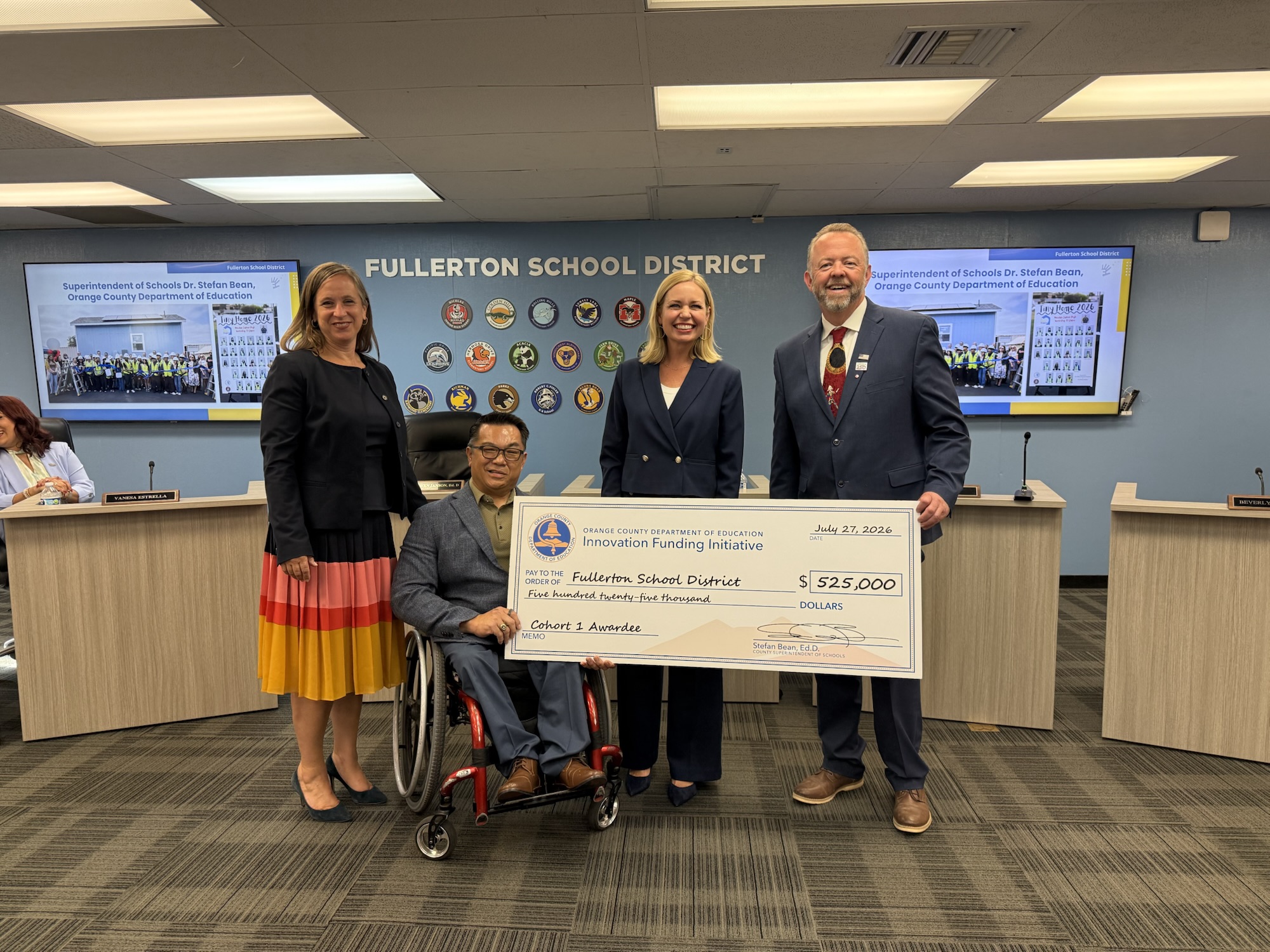 Four education leaders pose at the Fullerton School District Board of Education meeting on July 27, 2026, holding a large ceremonial $525,000 check from OCDE’s Innovation Funding Initiative.